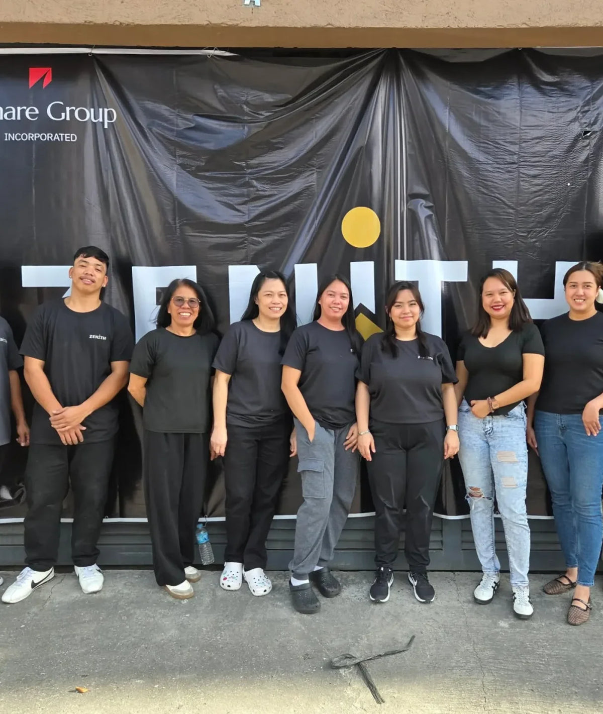 Zenith team in black shirts standing in front of a Zenith banner
